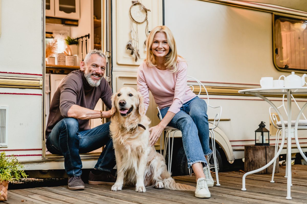 Couple sitting with their dog in front of their RV